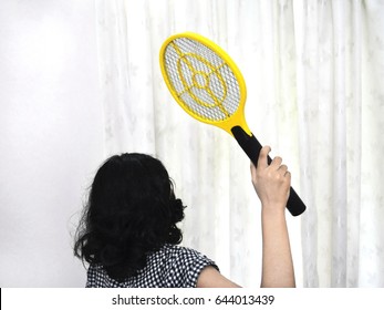 Girl Trying To Swat Mosquitoes With An Electronic Mosquito Racket.