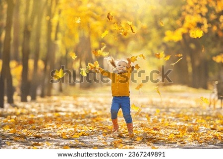 A girl with two ponytails throws autumn leaves in the park