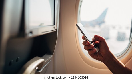 Girl Typing Message In The Plane. Woman In The Plane Holding Mobile Phone.