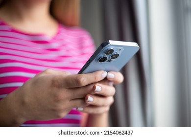 Girl typing sms on modern mobile phone with triple camera. Young white woman communicating online with smartphone. Female person messaging on social media app with new trendy cellphone