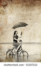 Girl with umbrella on bike. Photo in old image style.