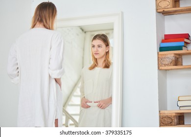 Girl unhappy with their appearance looks in the mirror