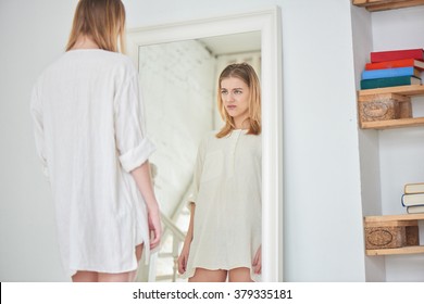 Girl unhappy with their appearance looks in the mirror