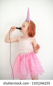 A Girl In A Unicorn Costume Sings Into A Microphone