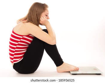 girl upset more weight, looks at the scales, isolated on white background