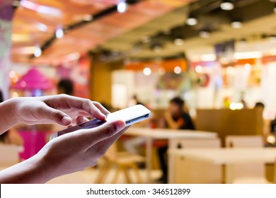 Girl Use Smart Phone ,blur Image Of Food Distribution Center In The Mall.