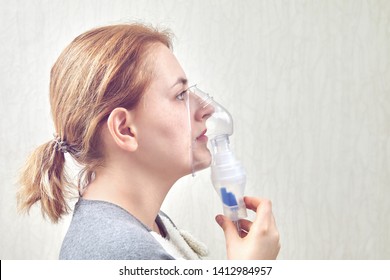 Girl Uses Inhaler Nebulizer For Treatment Respiratory Disease. She Is Breathing With Help Of Nebulizer Chamber.