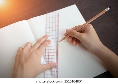 A Girl Uses A Pencil And A Ruler Draws A Straight Line.