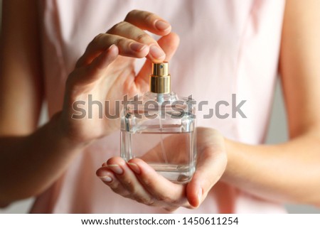 The girl uses perfume. Perfume in female hands.
