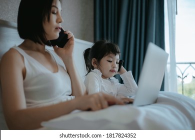 The Girl Uses The Phone While Mom Is Working