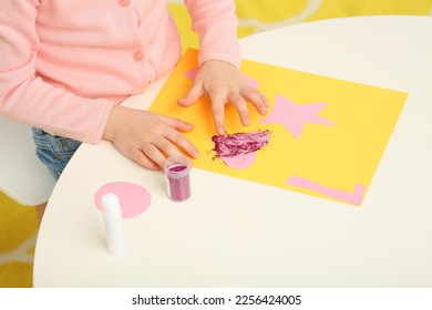Girl using colorful glitter while making paper card at desk in room, closeup. Home workplace - Shutterstock ID 2256424005