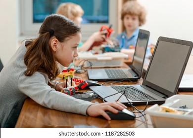 Girl Using A Laptop While Assembling A Robot From Plastic Bricks. STEM Education For Kids.