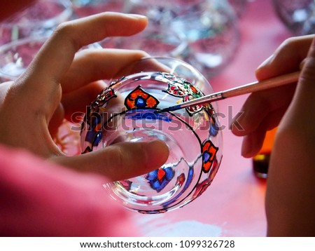 The girl is using a paintbrush painted on a glass. Handicrafts kids activity. Fun training for kids.