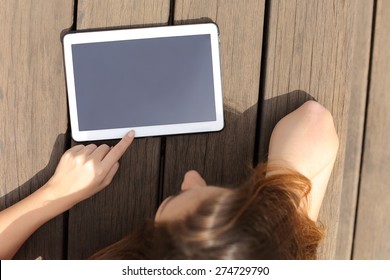 Girl using and showing a blank tablet screen lying in a bench in a sunny day