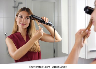 Girl Using Steam Straightener To Style Hair At The Mirror On Bathroom