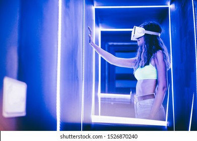 Girl using VR goggles in colorful neon lights, having fun. Girl in a VR glasses surprised with what she saw. Wearable virtual augmented reality digital innovation technology concept. - Shutterstock ID 1526870240