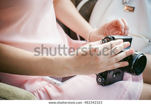girl with vintage camera in his hands. sitting in the\
car, the girl in a pink dress holding a retro camera, ready to\
shoot him
