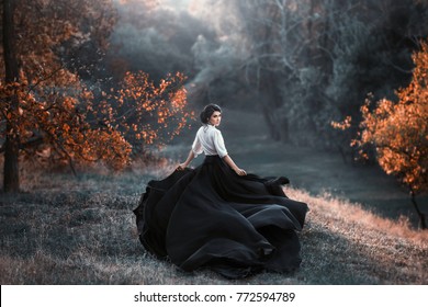 A girl in a vintage dress is running and looking around. The train waving in the wind. Art Photography. Landscape forest, orange trees. Gothic beauty, the dark queen. Wallpaper - Shutterstock ID 772594789
