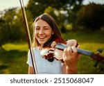 Girl, violin and happy in nature for music, talent and entertainment for event. Musician, string instrument and smile on grass for art, rehearsal and practice for creativity with skill development