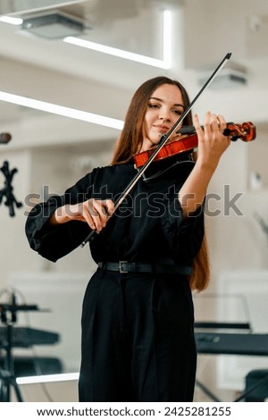 Girl violinist concentrates on performing classical melody during a violin rehearsal in a music center