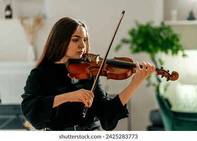 A girl violinist rehearses the melody of a classical piece of music on the violin in a music center at rehearsal - Powered by Shutterstock