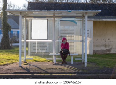 Girl waiting for the bus in a carport on sunny day