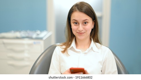 Girl Waiting For The Doctor At The Dental Office, Sitting On The Dental Chair, Swiping On Phone During A Visit. 4k Video Screenshot, Please Use In Small Size