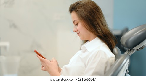 Girl Waiting For The Doctor At The Dental Office, Sitting On The Dental Chair, Swiping On Phone During A Visit. 4k Video Screenshot, Please Use In Small Size