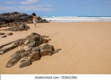 girl walking alone on Alexandria Beach in Noosa National Park, Queensland, Australia