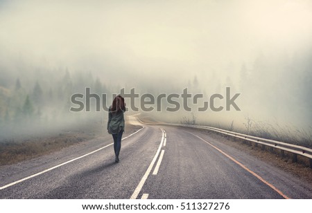 girl walking alone on mountain highway in winter foggy day