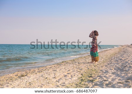 A girl is walking along the beach. A woman is walking along the sandy beach of the sea. A girl in Indian clothes enjoys the ocean.