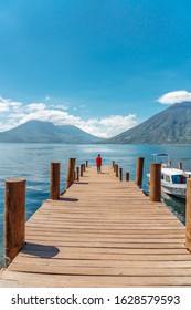 Girl Walking Along Jetty At Lake Atitlán Looking San Pedro Volcano And Atitlán Volcano, Guatemala