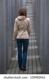 Girl Walking Away Through Grey Corridor