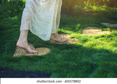 Girl Walking Barefoot On The Stones In Heart Shape On Green Grass, Concept Of Love For The Nature