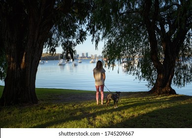 Girl walking her dog at Matilda Bay reserve at sunrise. Beautiful calm morning with no wind or clouds. 