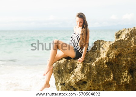 girl walking near ocean and rocks
