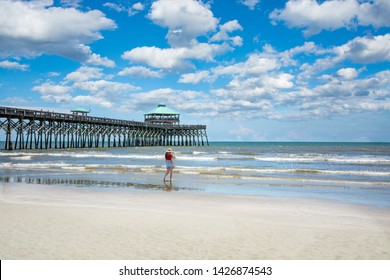 Girl walking on the beautiful beach, Woman relaxing on summer vacation by the ocean. Cloudy sky and pier in the background. Folly Beach, South Carolina USA.  - Powered by Shutterstock