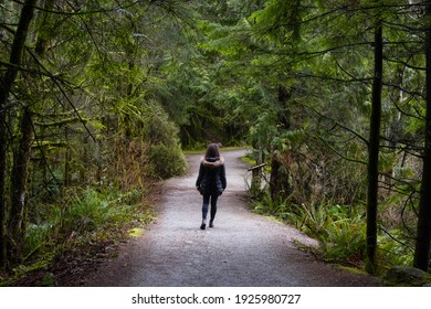 Girl Walking On A Beautiful Path In The Rainforest During A Wet And Rainy Day. Lynn Canyon Park, North Vancouver, British Columbia, Canada. Nature Forest Background