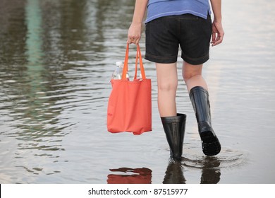 girl walking on flooded street,carrying fresh water for drinking.