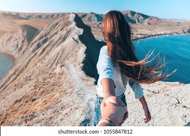Girl walking on the mountain top over blue sea view. Follow me - POV.