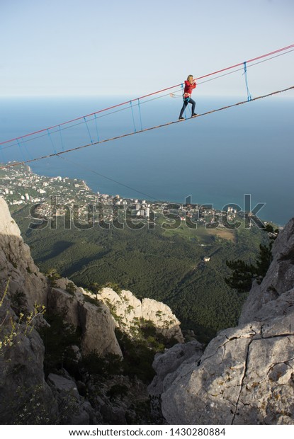 Girl walking\
on a rope bridge in the mountains. \
Walk The Ai Petri Bridges\
Crimea. Walking in the clouds. \
It is one of the windiest peaks\
and the most famous Crimean\
mountains.
