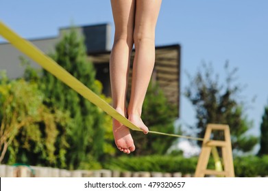 Girl walking on the sling. Child balancing on slackline at a beach. Shadow of a human figures on the sand. Girl is balancing on one leg. - Powered by Shutterstock