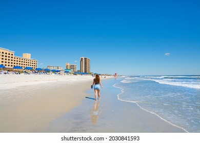Girl walking and relaxing on the beach on the summer morning. Beautiful clear blue sky. Buildings and hotels in the background. Jacksonville, Florida, USA. Copy space.