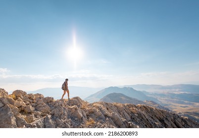 A girl walks along a mountain road against the blue sky and mountains. travel and adventure in the mountains. Alpinism and rock climbing.
 - Powered by Shutterstock