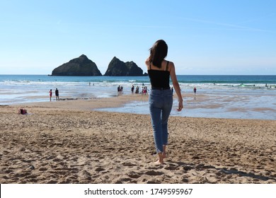 Girl walks along the sand at Holywell Bay, Cornwall