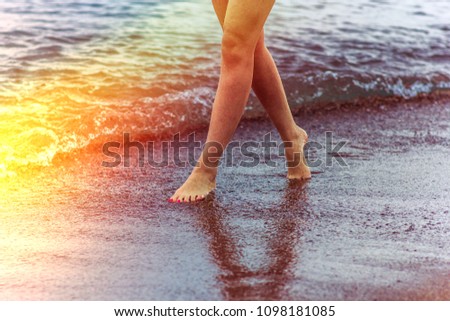 A girl walks along the seashore at sunset time
