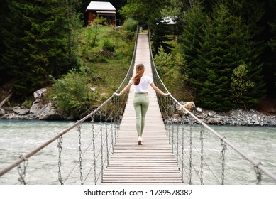 A girl walks on a bridge across the river