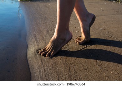 a girl walks on the sandy shore with bare feet on the sand and the beach, feet are on the sand
 - Powered by Shutterstock