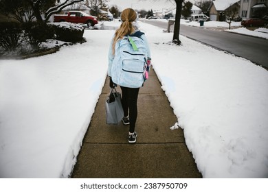 Girl walks to school through snow covered yards in winter - Powered by Shutterstock