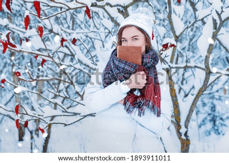 The girl walks through the winter forest. She covered her face with a book. Learning concept. Winter's tale. Mixed media